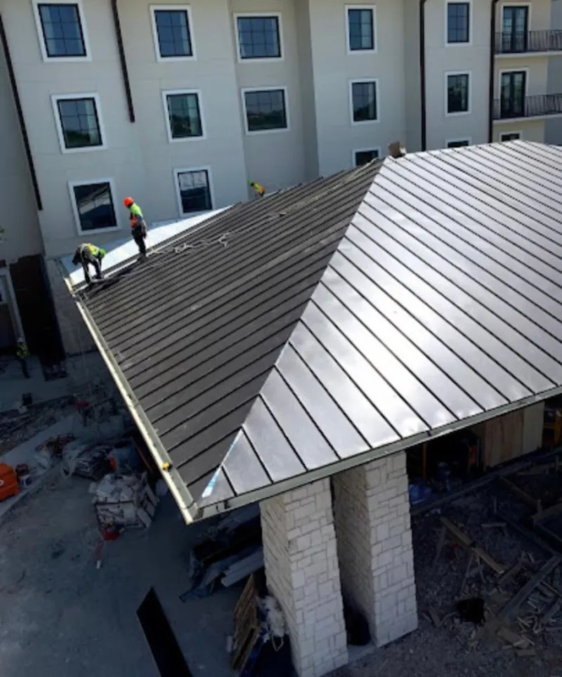Crew installing standing seam metal roof panels on a commercial project in Ashton-Sandy Spring